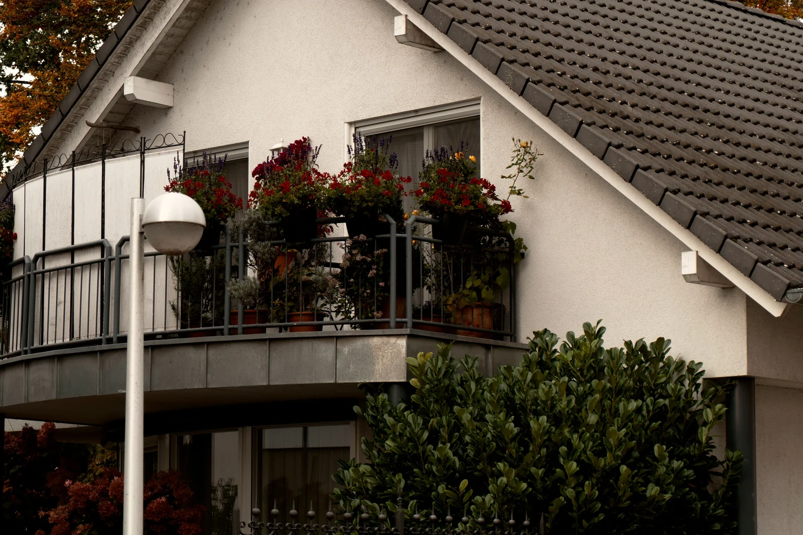Wohnhaus mit Balkon und herbstlicher Bepflanzung